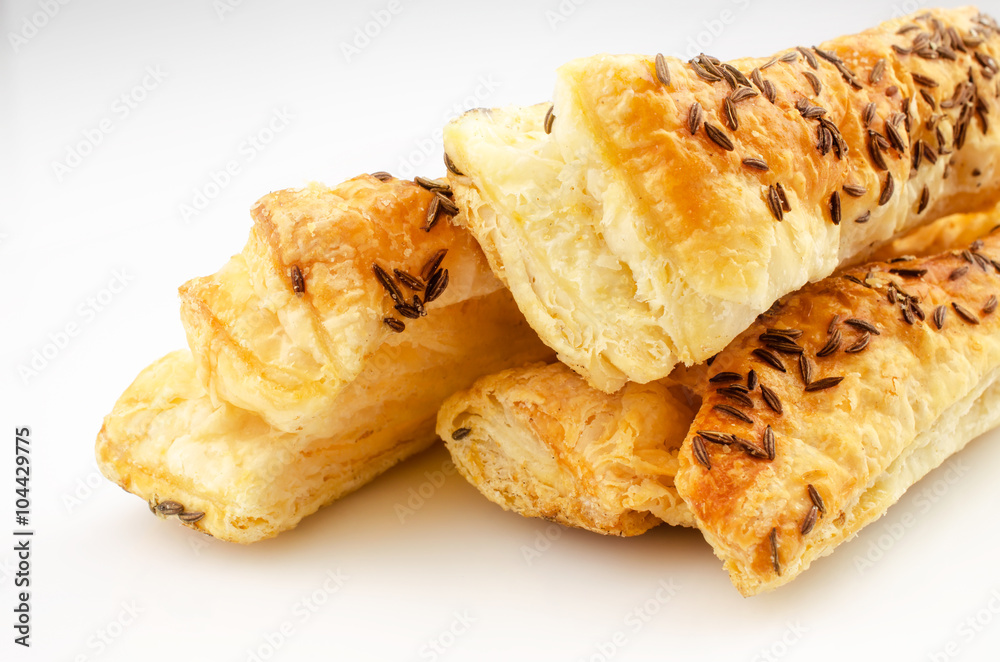 Confectionery theme. Puff pastry, topped with caraway seeds, on white surface. 