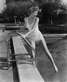 Woman dipping toes in outdoor swimming pool 