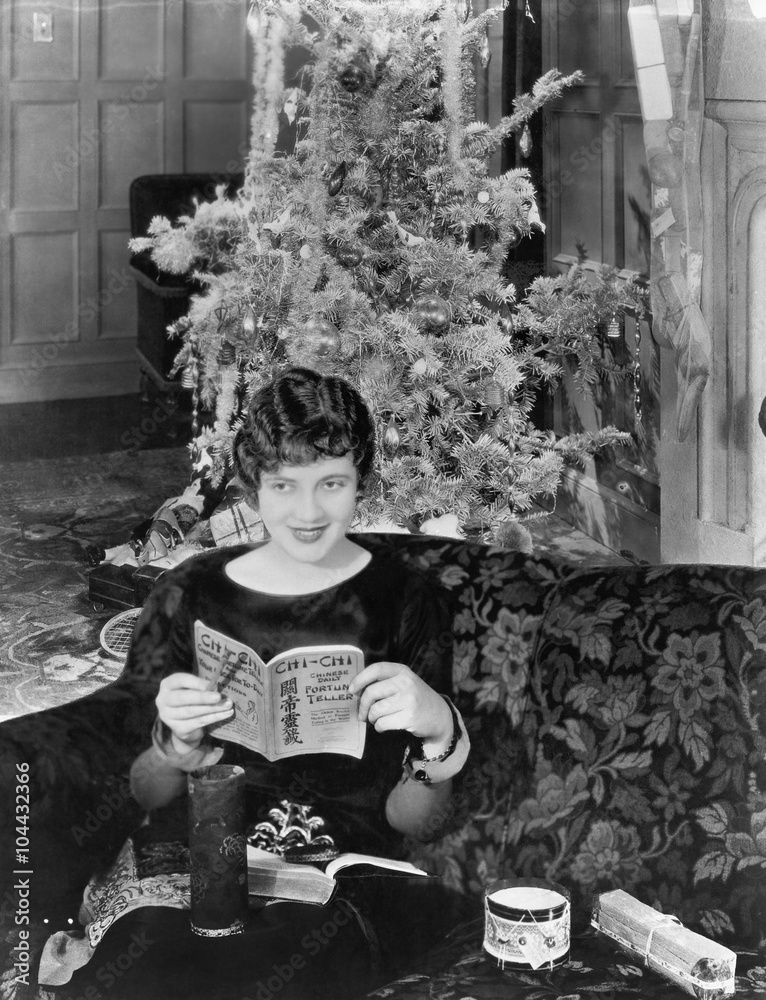 Young woman sitting on a couch with a Christmas tree in the background 
