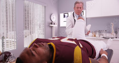 Mid-aged physical therapist examining college athlete sports inj photo