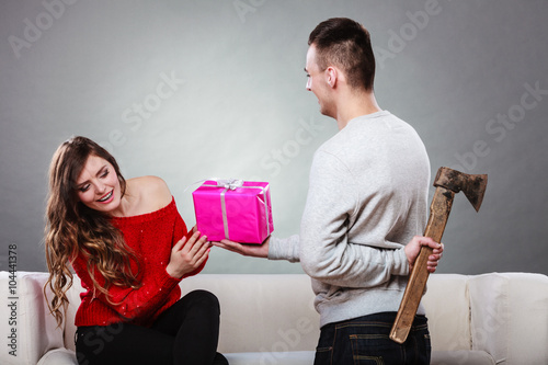 Φωτογραφία Insincire man holding axe giving gift box to woman