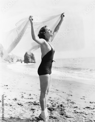 Profile of a young woman holding up a sarong at the beach  photo