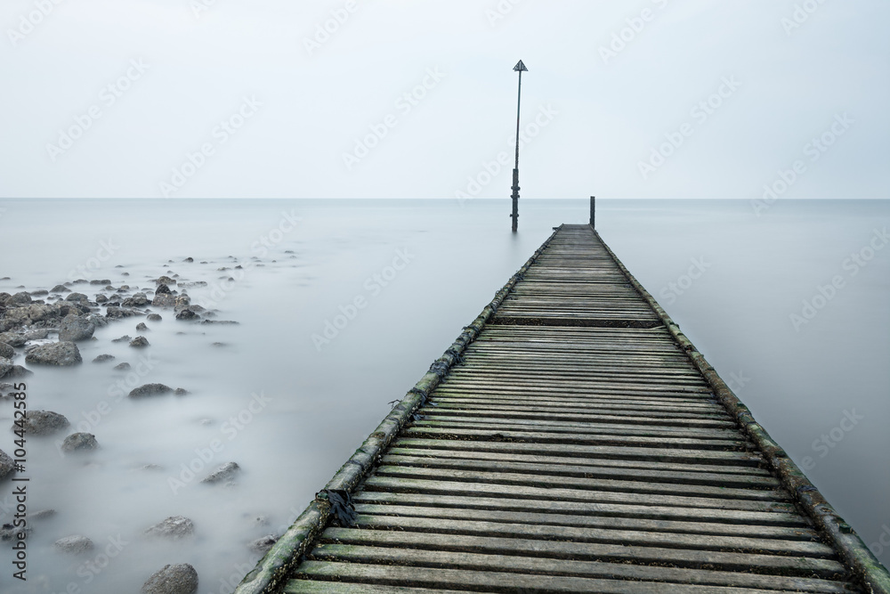 Long abandoned rotted jetty leading out to sea on a cold misty afternoon in Llandudno, Wales, UK.