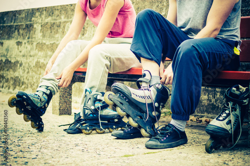 People friends putting on roller skates outdoor.