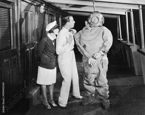 Two people looking in shock at a diver in a divers suit 