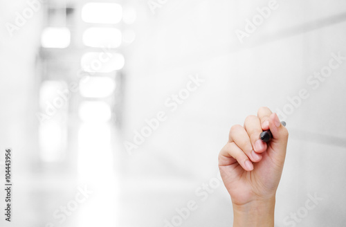 Hand holing pen over blurred office background