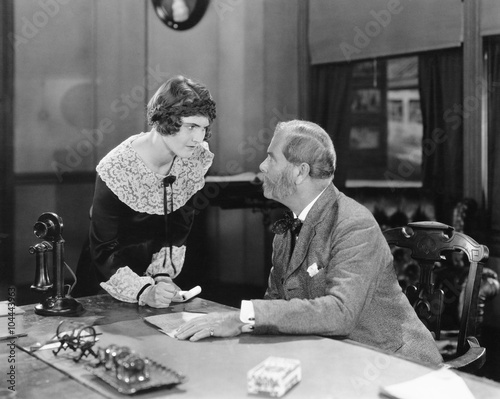 Woman with fist clenched in an office glaring at her boss  photo