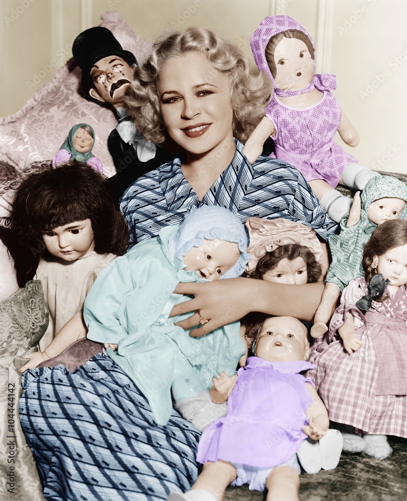 Portrait of a woman surrounded by dolls and smiling Portrait of a woman surrounded by dolls and smiling