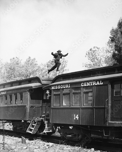 Man leaping across the roof of railroad cars 
