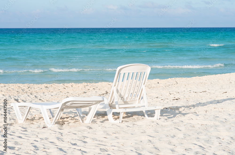 White plastic chairs on white sand beach White plastic chairs on white sand beach