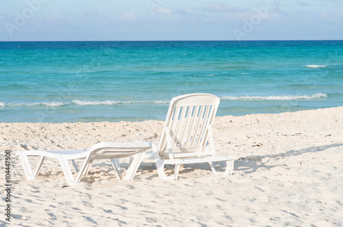 White plastic chairs on white sand beach
