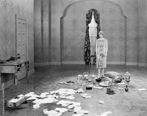Tableau sur toile Woman standing in an empty room scattered with letters