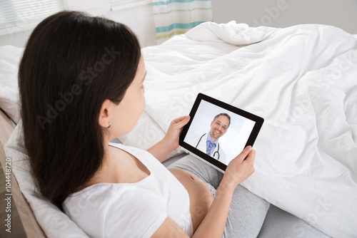 Pregnant Woman Talking To Doctor On Digital Tablet