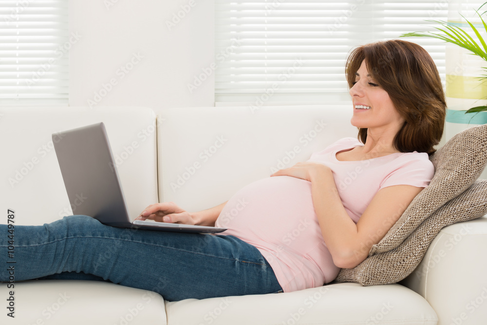Pregnant Woman Relaxing On Sofa With Her Laptop Pregnant Woman Relaxing On Sofa With Her Laptop