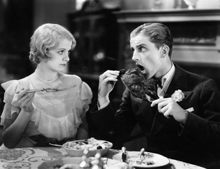 Man eating a roasted turkey with woman 