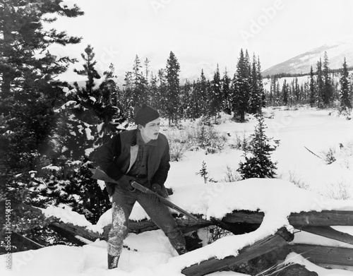 Hunter with his rifle walking through snow covered countryside  photo