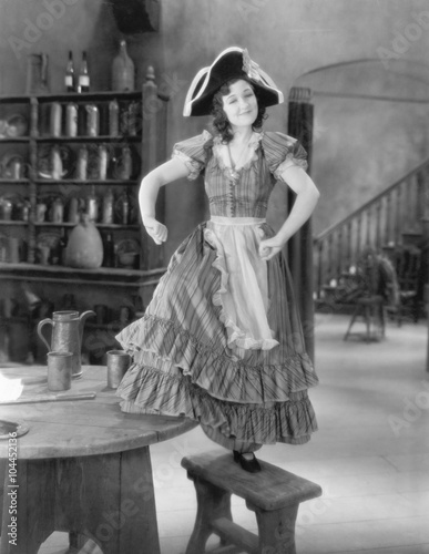 Young woman with a buccaneer hat dancing on a chair 