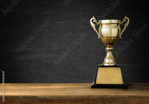 Trophies placed on a wooden table with blackboard background