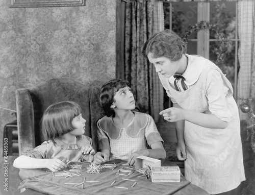 Billede på lærred Woman scolding her two daughters for playing with matchsticks
