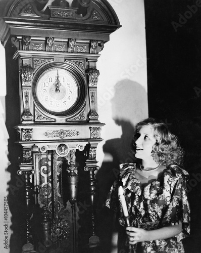 Woman with grandfather clock at midnight 