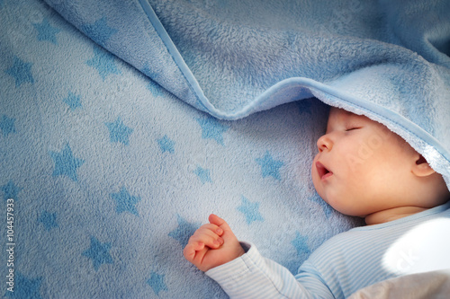 three month old baby sleeping on blue blanket photo