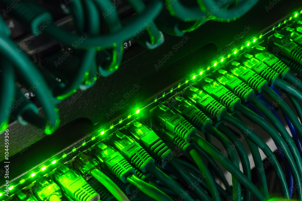 Close up of green network cables connected to switch glowing in the dark