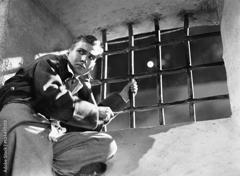 Fototapeta premium Low angle view of a young man trying to escape from a prison cell 