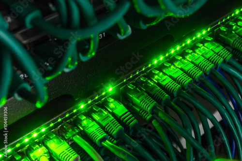 Close up of green network cables connected to switch glowing in the dark