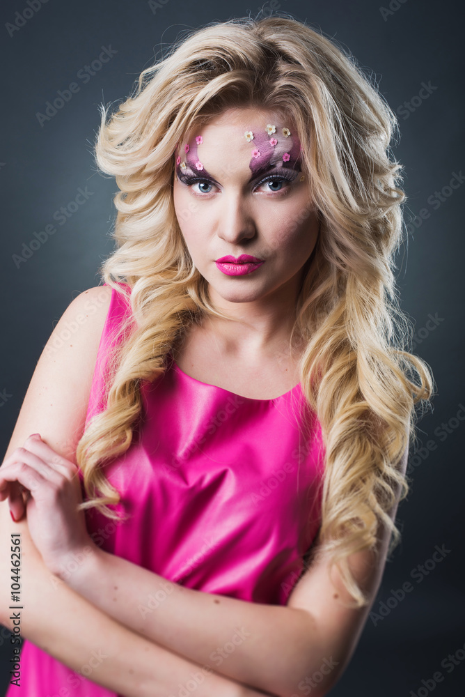 sexy blonde girl with art makeup posing in the studio on a dark background wall. Pink image. Makeup with flowers. sexy blonde girl with art makeup posing in the studio on a dark background wall. Pink image. Makeup with flowers.
