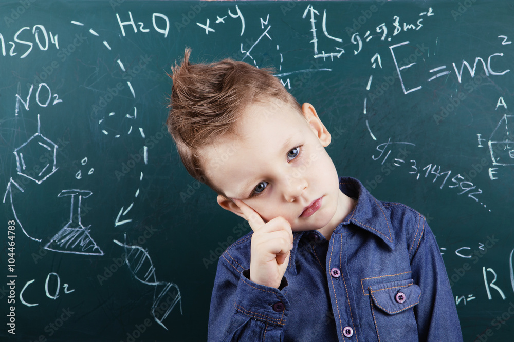 Little boy near blackboard with formulas