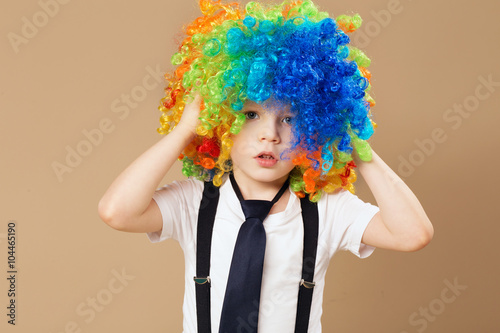 Little boy in clown wig smilling and having fun