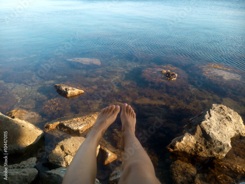 Женские ноги на морском скалистом берегу летний отдых