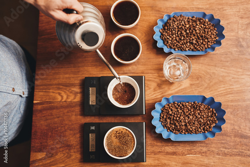 Barista pouring water into cup of ground coffee on scale photo