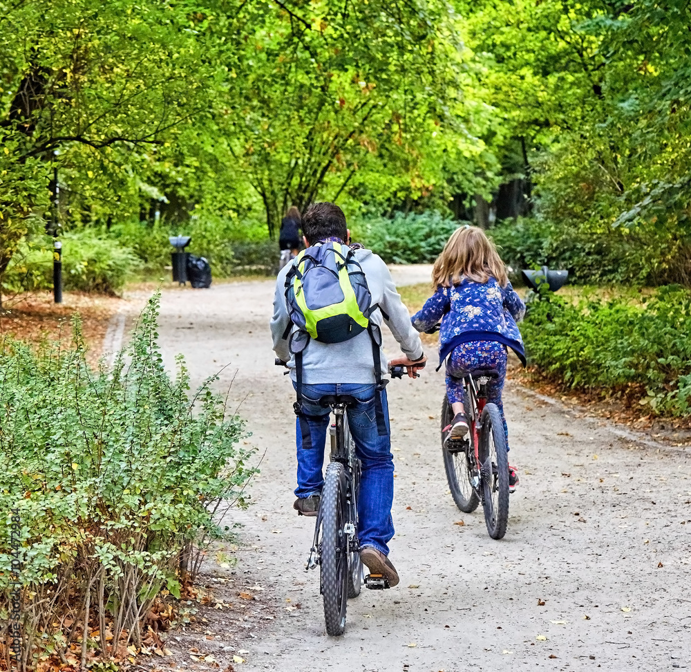 Obraz premium Father and daughter enjoy riding on bikes in park