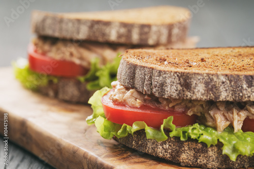Obraz na płótnie rye bread sandwich with tuna and vegetables on wood background