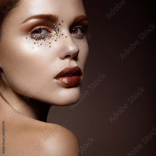 Fotografie Beautiful girl with a gentle make-up and crystals on the face.