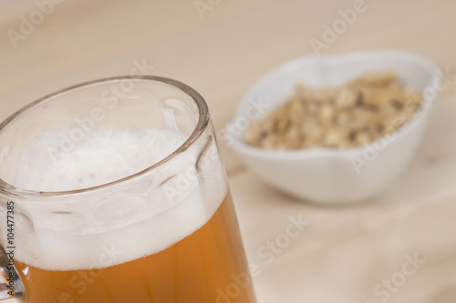 Draft beer and peanuts in the bowl on wood table