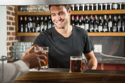 Photos Handsome bar tender giving a pint to customer