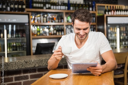 Handsome man using tablet and having coffee