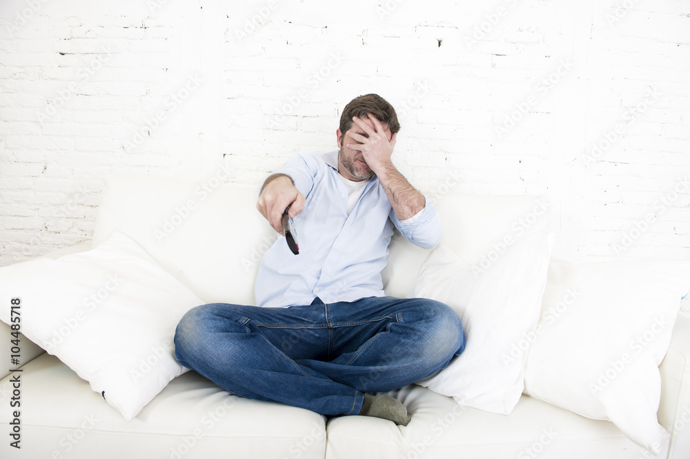 young happy man watching television horror movie covering his eyes scared and horrified young happy man watching television horror movie covering his eyes scared and horrified