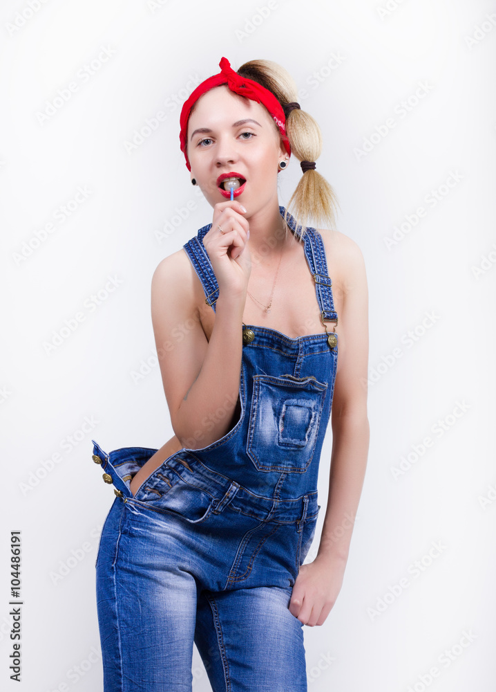 Beautiful young leggy blondy girl in a red bandana, denim overalls over his  naked body, licking candy Stock Photo | Adobe Stock