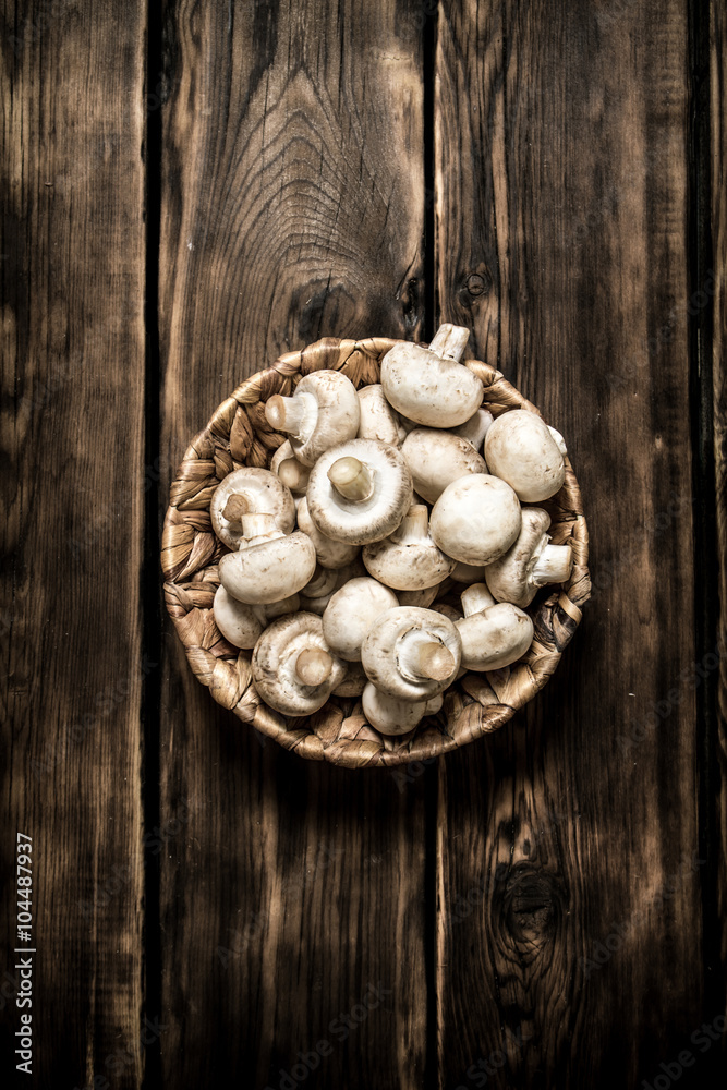 Fresh mushrooms in basket. On wooden background.