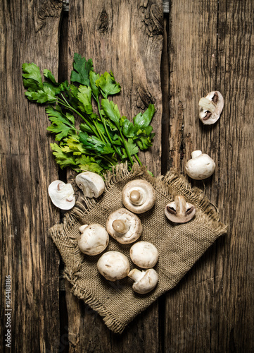 Parsley and fresh mushrooms. On wooden background.
