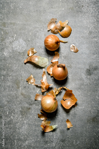 Foto Fresh onions from the husk. On stone background.