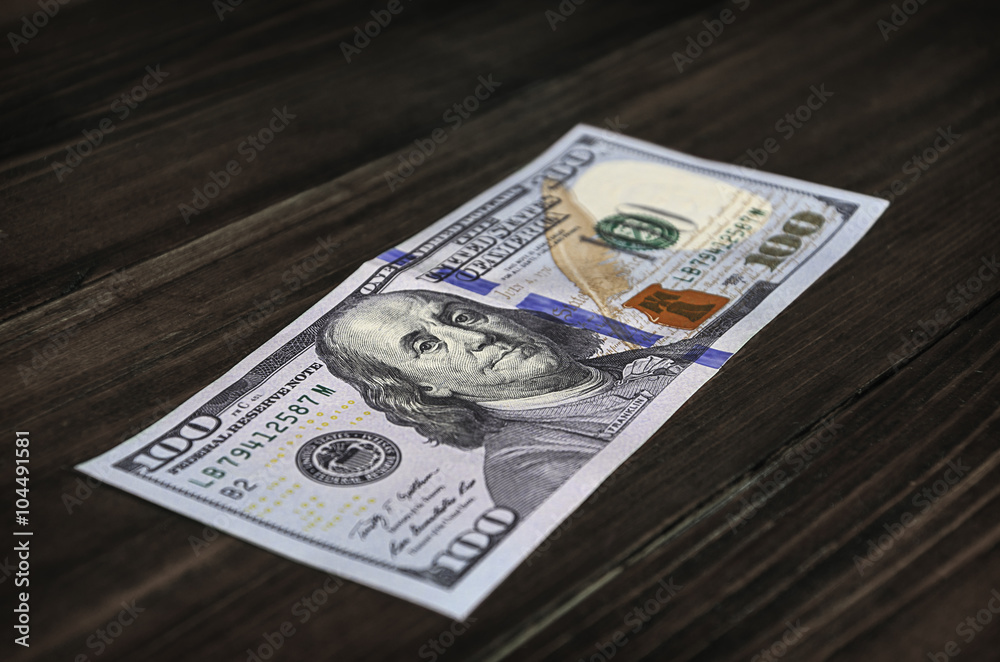 Bancnote of 100 dollars on a wooden table Bancnote of 100 dollars on a wooden table