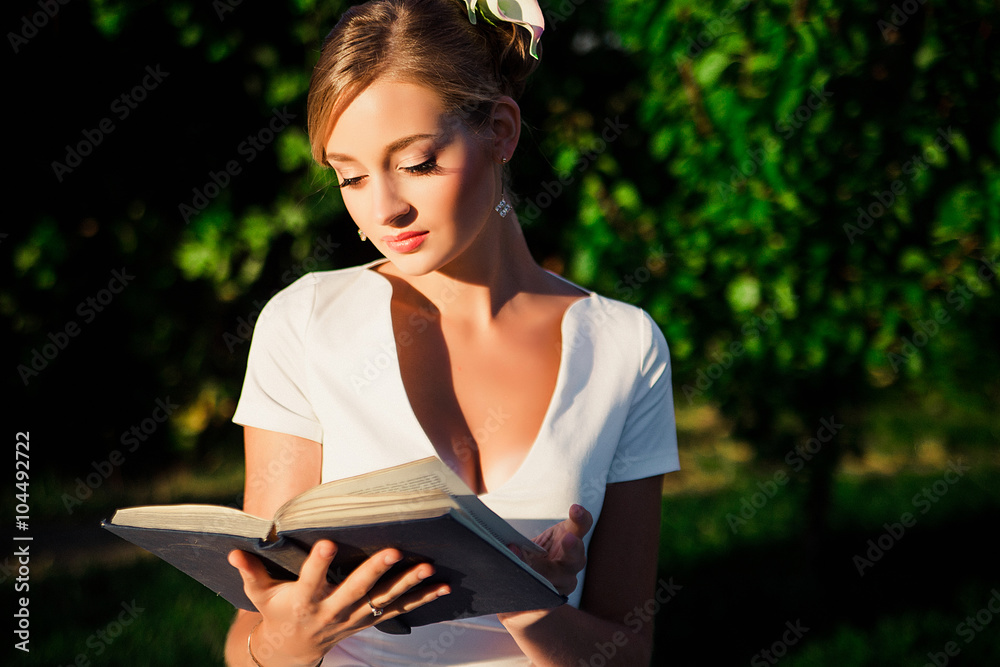 Obraz premium Beautiful romantic woman in light dress posing in a blooming gar