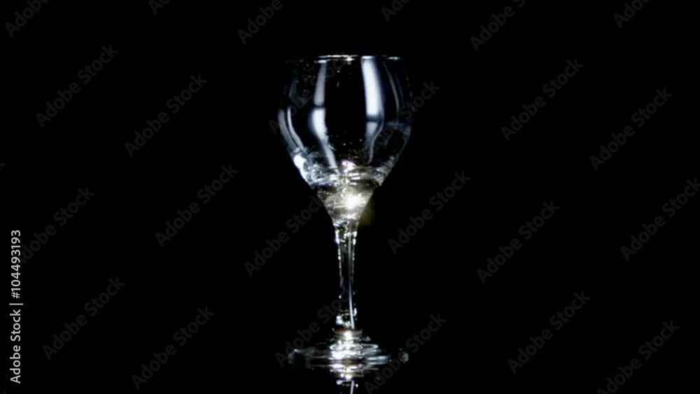 Glass of wine being poured from unseen bottle on a black background. Glass of wine being poured from unseen bottle on a black background.