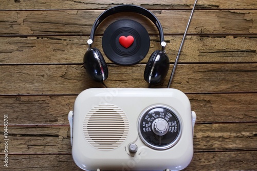 Vintage radio with a black vinyl record and a set of headphones on a rough wooden background