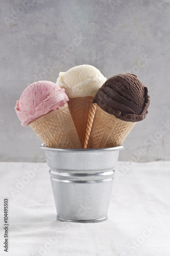 Strawberry, vanilla and chocolate ice cream cones and scoop.