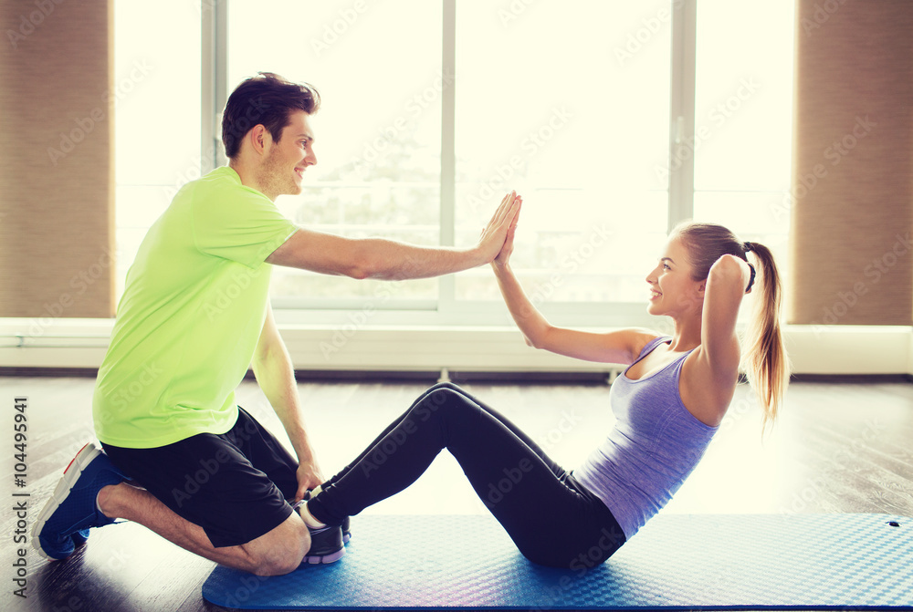woman with personal trainer doing sit ups in gym woman with personal trainer doing sit ups in gym